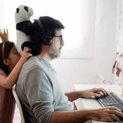 Supporting your workforce - Dad working from home with his  young daughter standing behind him
